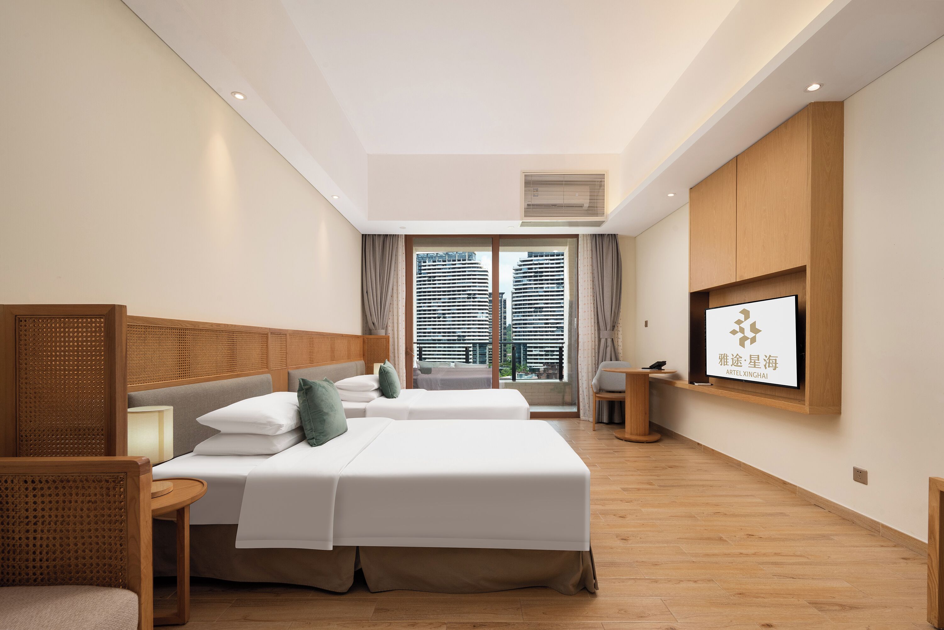 A hotel room with two beds, a TV mounted on the wall, and a large window with blinds.