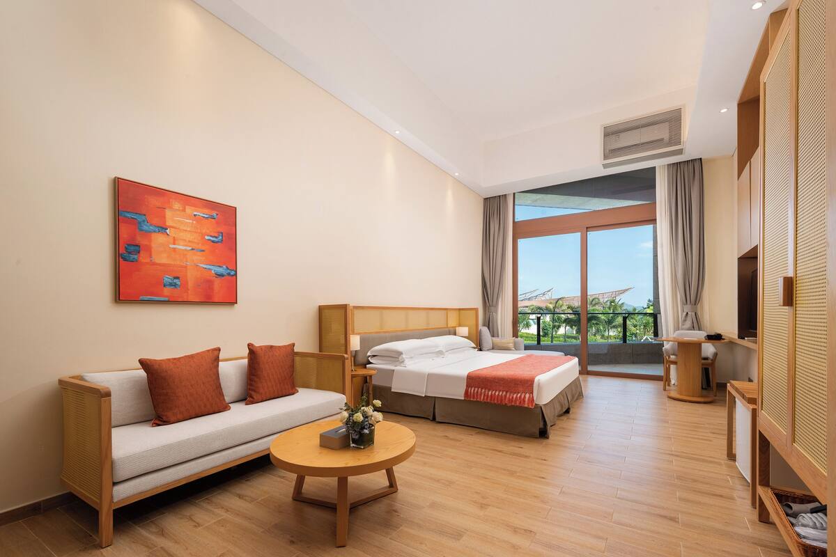 Una habitació d'hotel moderna amb un sofà, un llit, una taula rodona i una finestra gran que ofereix vistes a l'exterior.