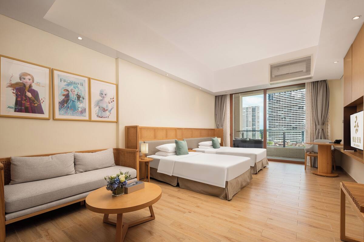 Habitació d'hotel amb un sofà, dos llits individuals, una taula rodona i una televisió.