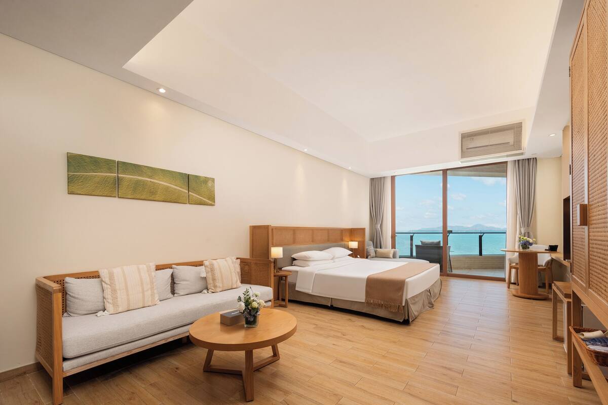 Habitació d'hotel moderna amb llit, sofà i un balcó amb vistes.