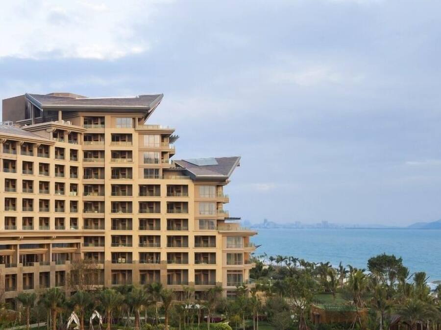 Ein mehrstöckiges Hotel mit modernem Design, ausgestattet mit Balkonen und großen Fenstern. Es liegt in der Nähe eines Gewässers und bietet einen schönen Ausblick.