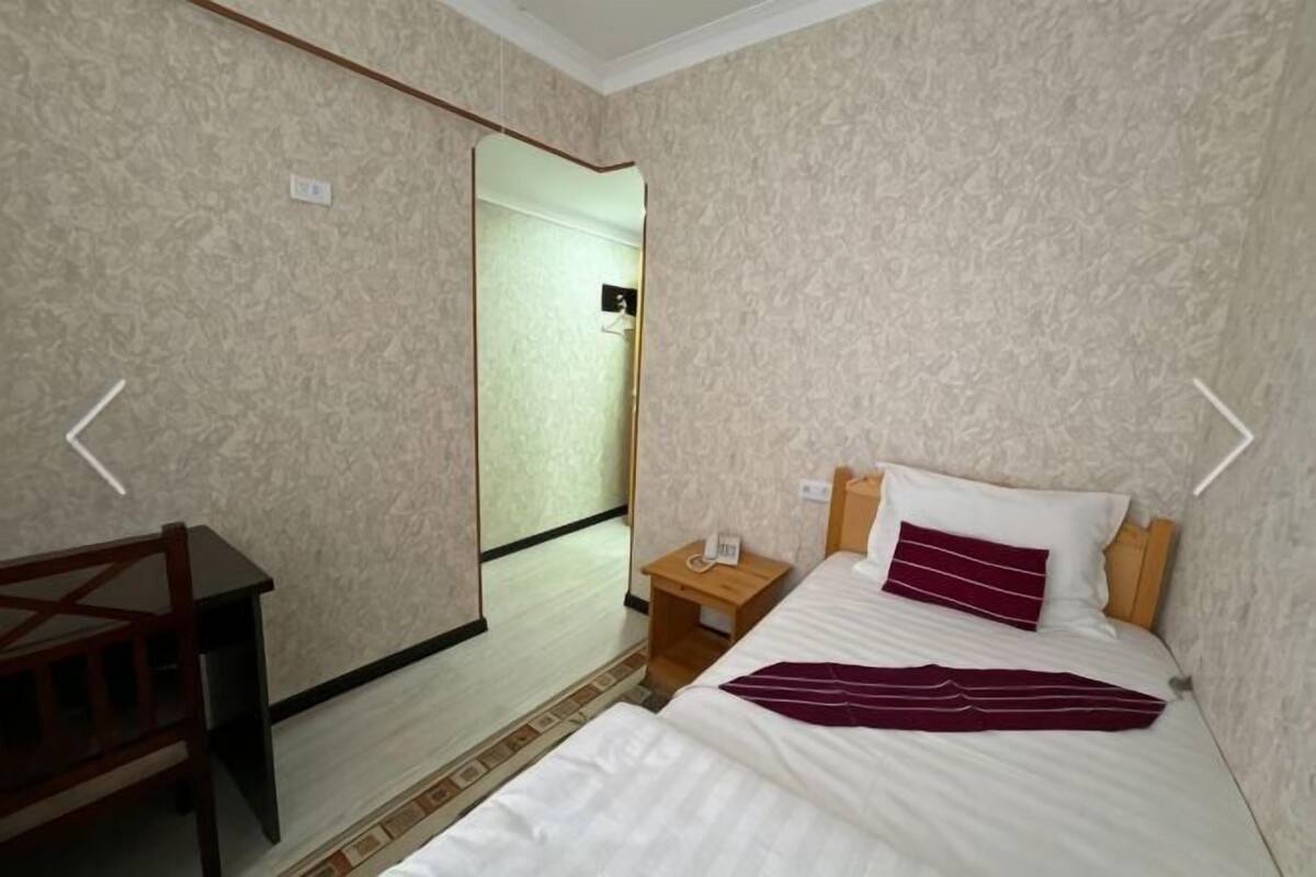 Una camera d'albergo con un letto, una scrivania, uno specchio e un comodino.