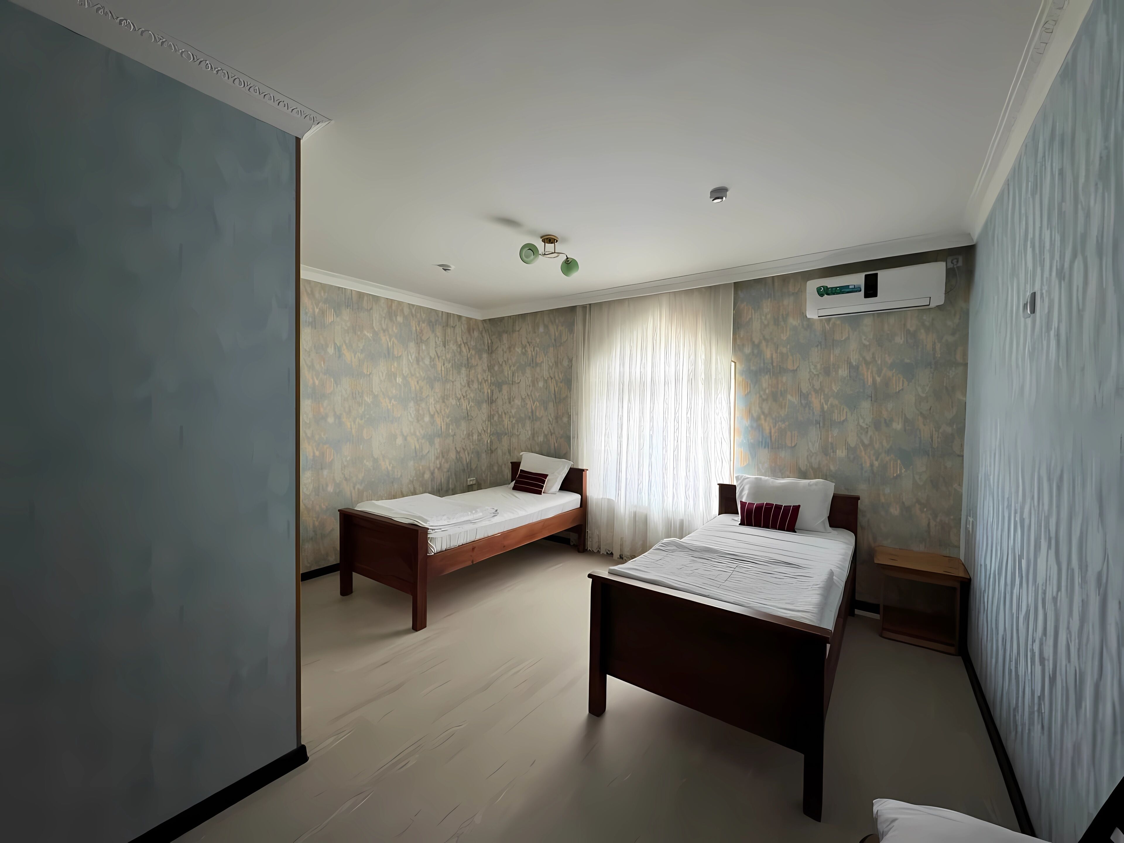 A bedroom with two single beds, a wooden floor, and a ceiling fan.