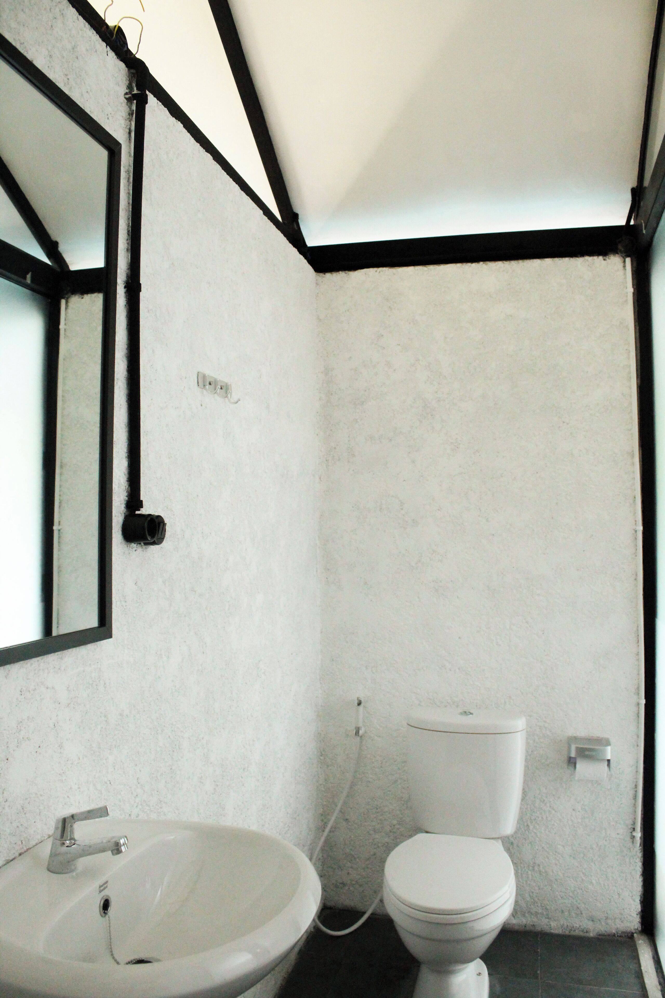 Un baño con lavamanos blanco, inodoro y espejo.