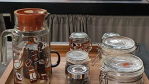 Una encimera de cocina con una cafetera, un hervidor y varios frascos de vidrio con bolsitas de té.