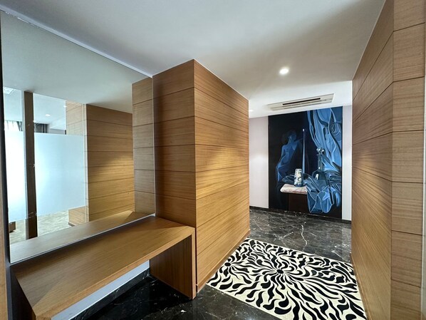 Un baño moderno con paneles de madera, piso de mármol y un espejo grande.
