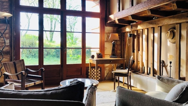 A rustic room with a large window, wooden furniture, and a radiator. - Le Mas Brantôme (Brantôme en Périgord)