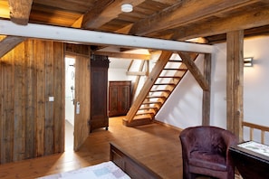 A wooden interior with a staircase, a chair, and a desk.