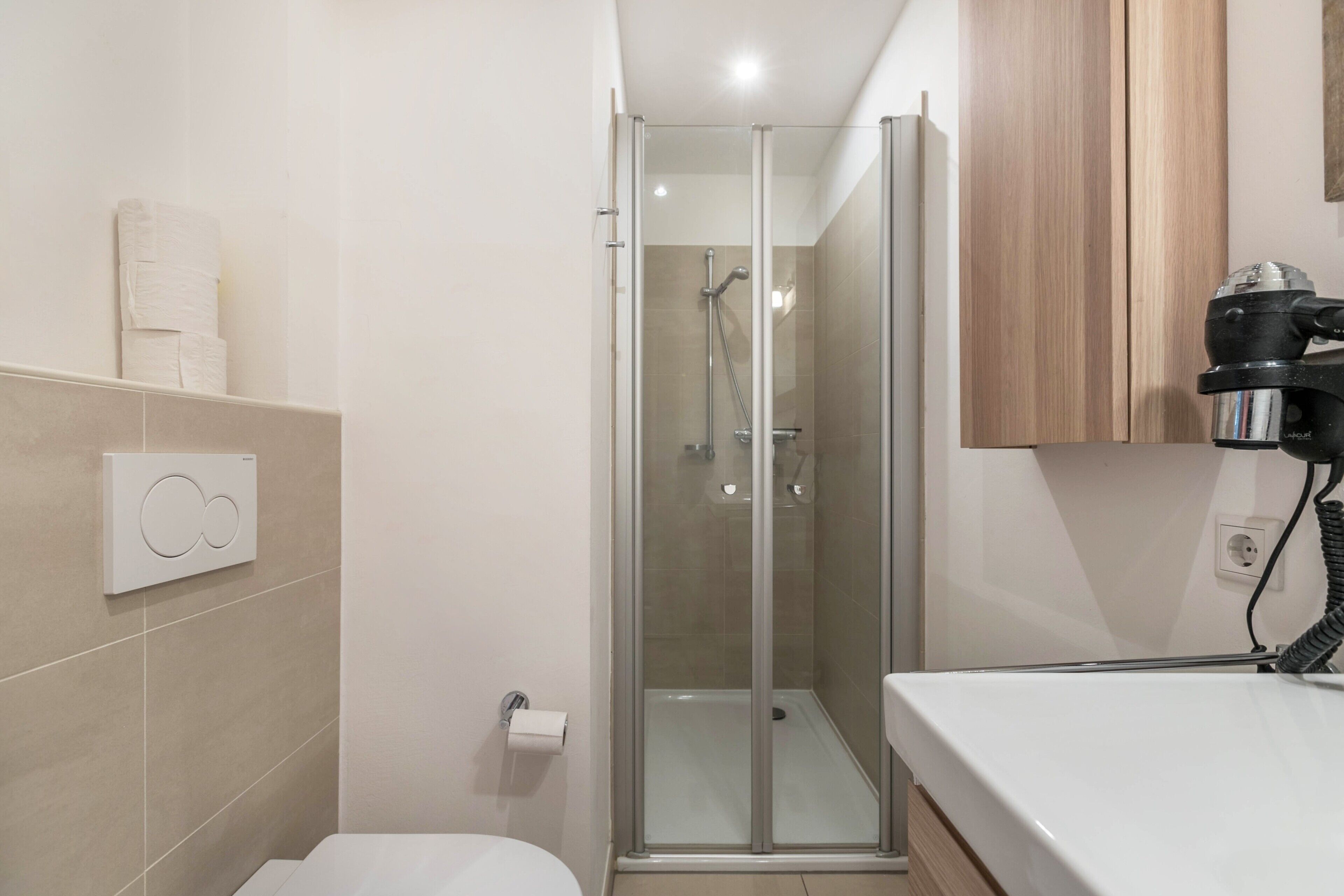 A bathroom with a glass-enclosed shower, a toilet, and a sink.