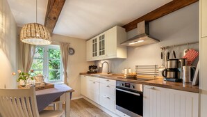 A kitchen with white cabinets, a wooden countertop, a stove, and a hanging light fixture.