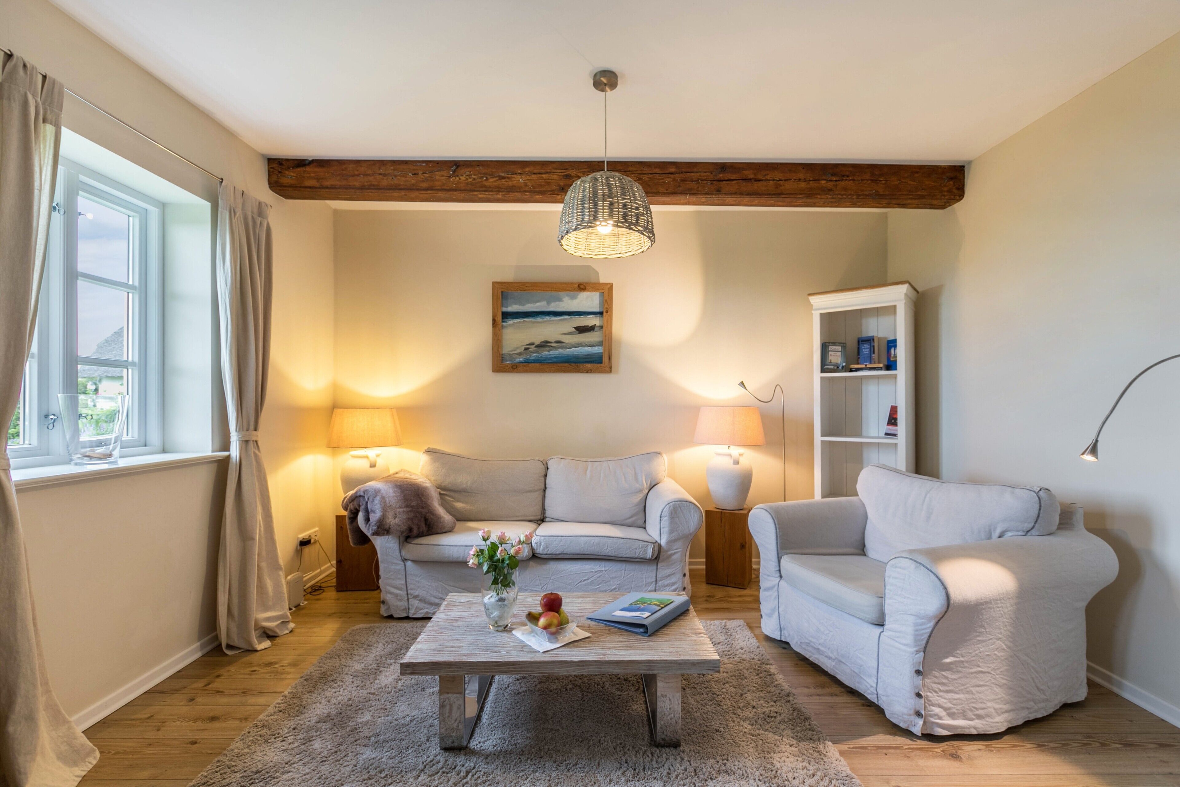 Una sala de estar con sofá, sillón, mesa de centro y estantería.