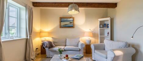 Una sala de estar con sofá, sillón, mesa de centro y estantería.