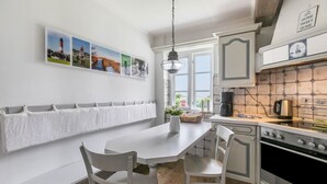 Eine Küche mit weißer Arbeitsplatte, einer Hängeleuchte und Blick ins Freie durch ein Fenster.