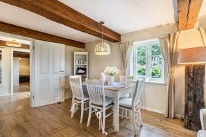 Un espace repas avec un plafond en bois, des chaises blanches, une table et un luminaire suspendu.