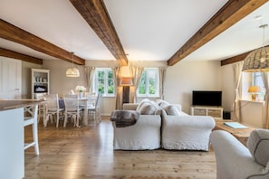 Une pièce spacieuse avec un plafond en bois, un ensemble de canapés, un coin repas et un téléviseur.