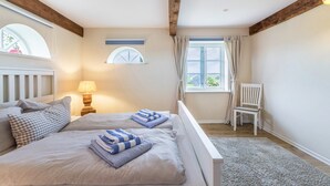 A bedroom with a bed, a chair, a window with curtains, and a lamp.