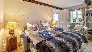 Un dormitorio con cama, lámparas de noche, una silla y una estantería.