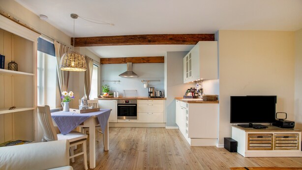 Un espacio habitable moderno con cocina, comedor y televisor.