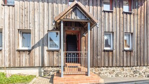 A wooden building with a porch, a stone foundation, and a metal gate.