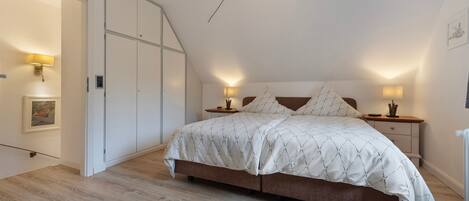 A bedroom with a bed, bedside tables, a lamp, a picture on the wall, and a door.