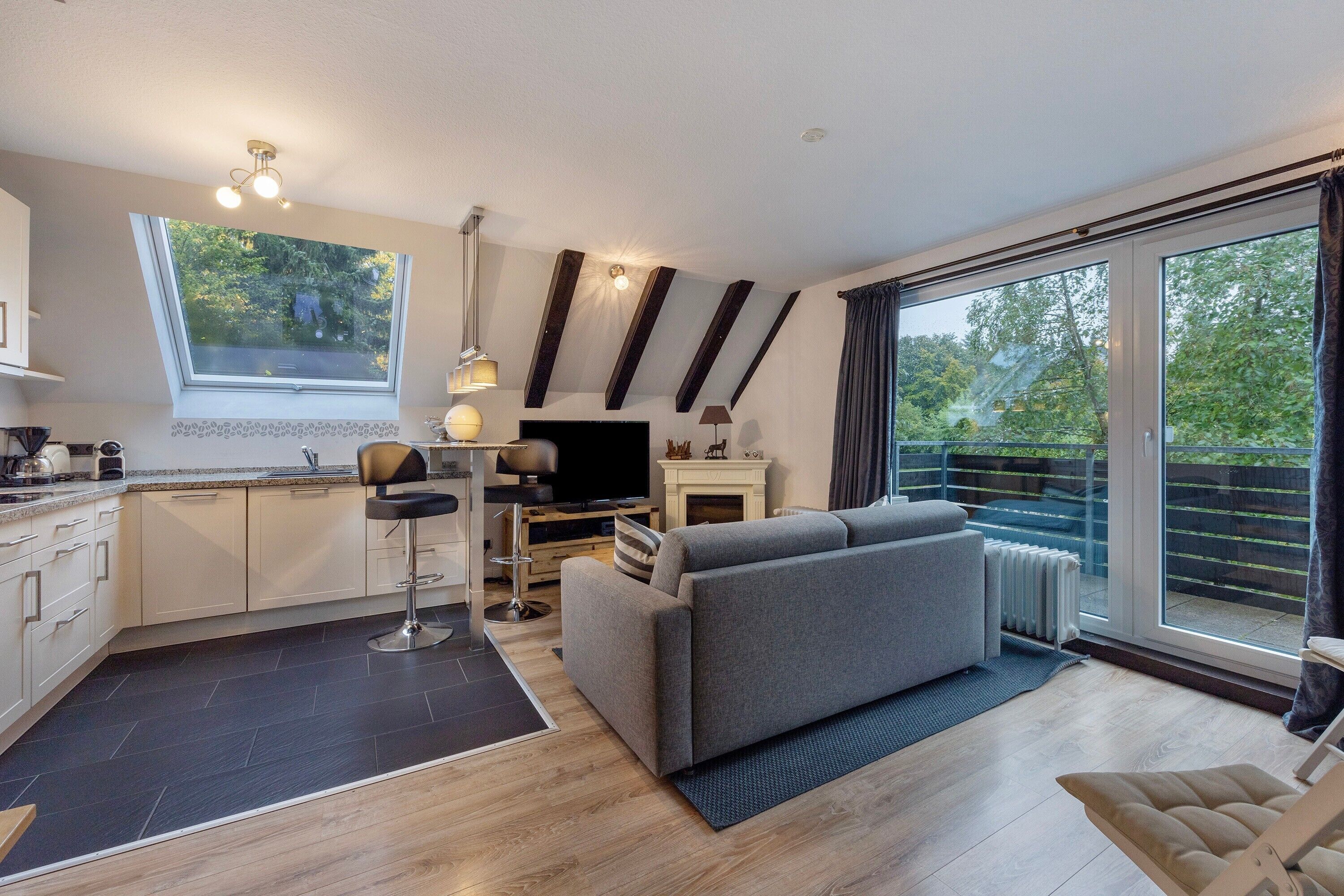 A modern apartment with a kitchen, dining area, and living room. It features a large window, a fireplace, and a sliding glass door to the outside.