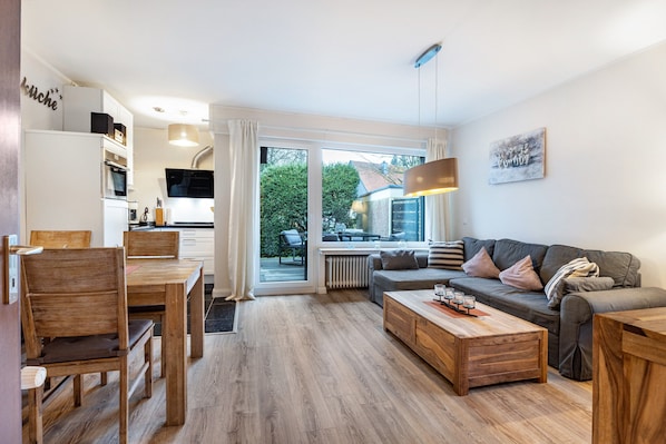 Un salon moderne comprenant un canapé, une table basse et un coin repas avec des chaises et une table.