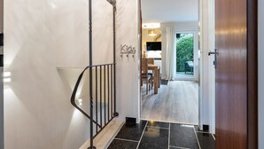 A hallway with a black tiled floor, a wooden door, and a coat rack with a 'Kids' sign. - Apartment 'Schönes Leben 4' with Sauna, Shared Terrace & Garden (Goslar)