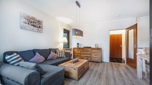 A modern living room with a sofa, coffee table, and wooden cabinets. - Apartment 'Schönes Leben 4' with Sauna, Shared Terrace & Garden (Goslar)