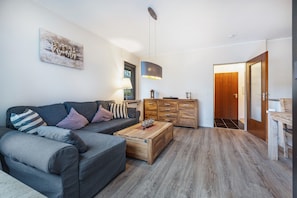 A modern living room with a sofa, coffee table, and wooden cabinets.