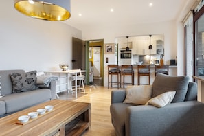 A modern living room with a sofa, coffee table, and dining area.
