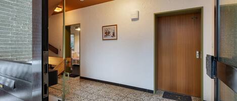 Un pasillo con una puerta de madera, un cuadro en la pared y una escalera que conduce a otra habitación.