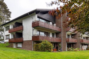 Un immeuble résidentiel à plusieurs étages, doté de balcons, d’une façade en briques et d’une pelouse bien entretenue.