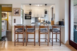 A modern kitchen with a central island, bar stools, and pendant lighting.