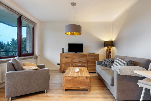 Un salon moderne avec un canapé, une table basse, un téléviseur et une lampe.