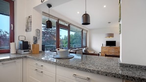 A modern kitchen with granite countertops, white cabinetry, and pendant lighting.