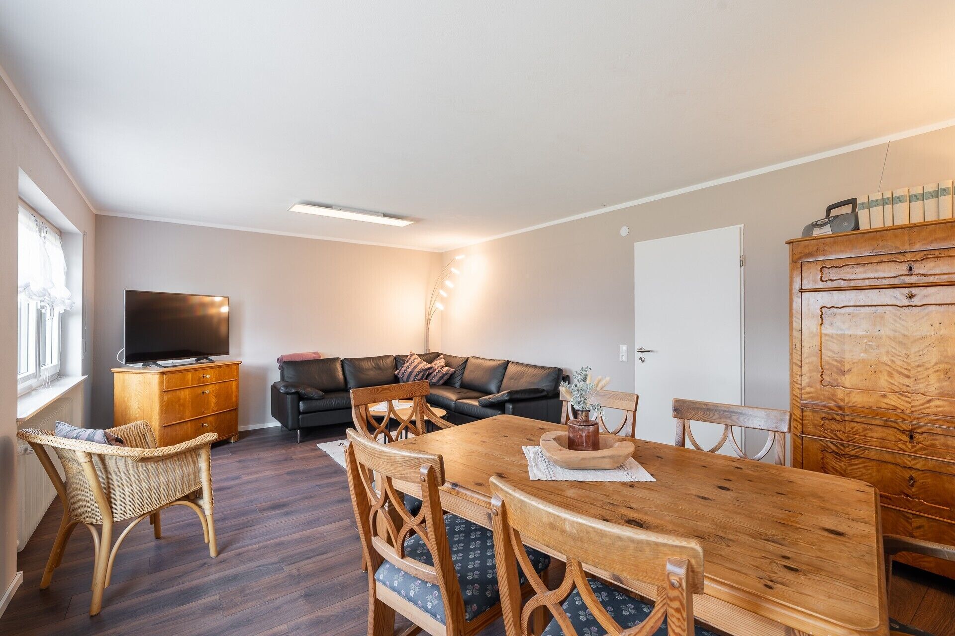 Un salon comprenant un canapé, une table à manger en bois, des chaises, un téléviseur et un meuble.