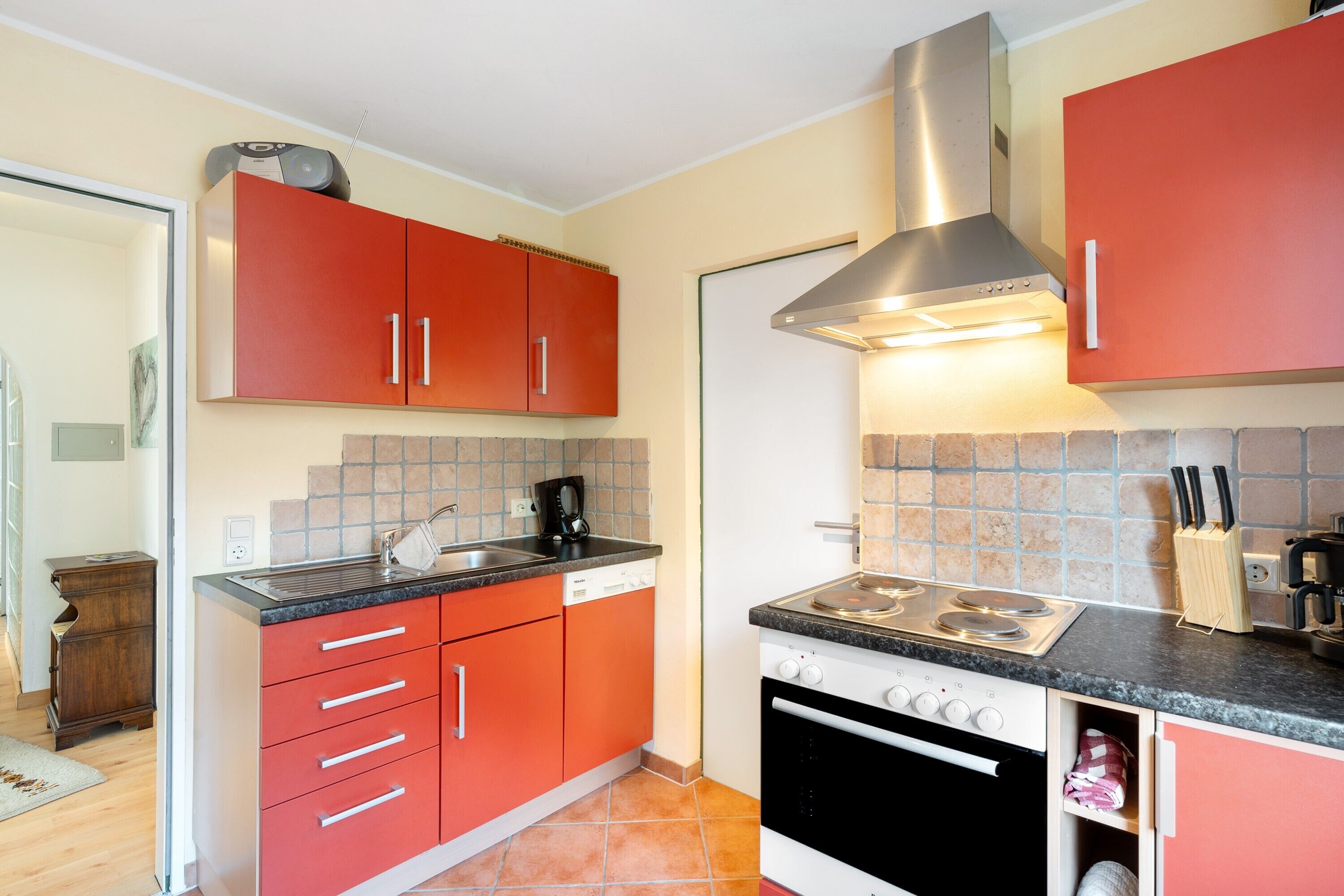 Una cocina con armarios rojos, una estufa y un lavamanos.