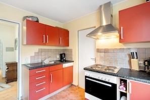 Une cuisine avec des placards rouges, une cuisinière et un évier.