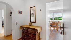 A room with a wooden dresser, a mirror, and a dining area with wooden chairs and a table.