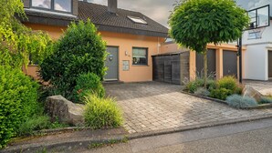 A residential house with a paved driveway, a garage, and a basketball hoop.