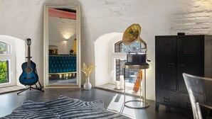Ein Zimmer mit Gitarre, Spiegel, Grammophon, Schrank und Teppich.