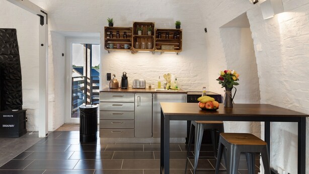 Eine moderne Küche mit Holztischplatte, eingebauten Regalen und einer Essecke mit Hockstühlen.