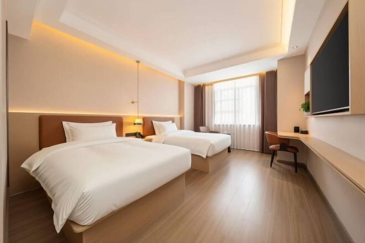 A hotel room with two beds, a desk, and a chair.