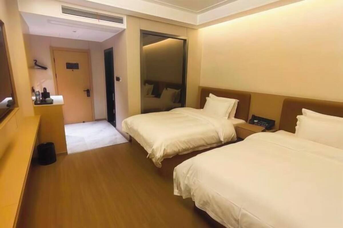 A hotel room with two beds, a small bathroom, and a mirror.