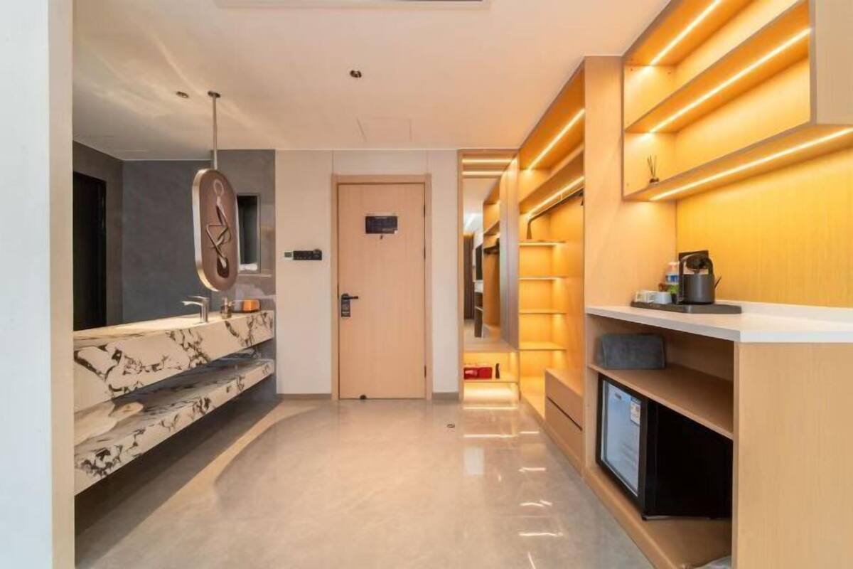 A modern hotel corridor with a marble vanity, a door with a sign, and built-in shelves with lighting.