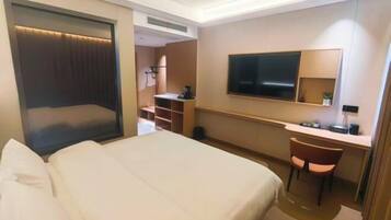 A hotel room with a bed, a desk, a chair, a television, and a wardrobe.