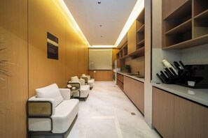 Una cuina moderna amb electrodomèstics integrats, zona de seients amb sofà i cadires, i taulell de cuina amb utensilis.
