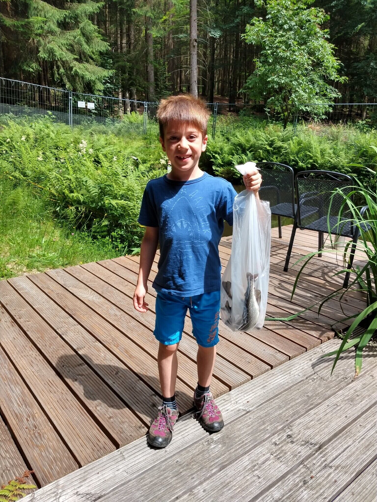 Ein Kind steht auf einem Holzboden und hält eine Plastiktüte.