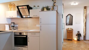A modern kitchen with white cabinetry, a built-in oven, and a coffee maker. - Grabmeier holiday flat - number 3’ with mountain view, balcony and Wi-Fi (Grainet)
