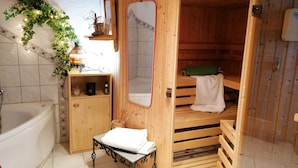 A wooden sauna room with a bench, a small table with a towel, and a mirror on the wall. - Grabmeier holiday flat - number 3’ with mountain view, balcony and Wi-Fi (Grainet)